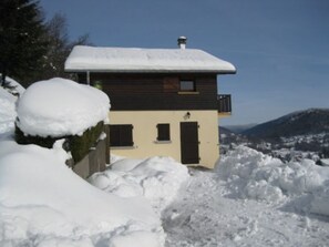 A two-story chalet with a snow-covered roof and a view of a snowy landscape. - Cozy Cottage in Vosges - Pets Allowed (Le Menil)