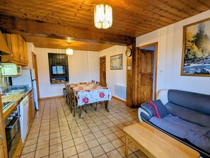 A cozy room with a dining table, a sofa, and a kitchen area. - Cozy Cottage in Vosges - Pets Allowed (Le Menil)