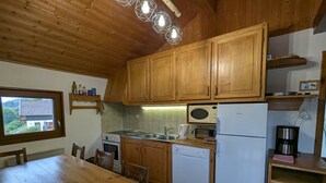 Eine Küche mit Holzschränken, einem Einbauofen, einer Mikrowelle, einem Spülbecken und einem Esstisch mit Stühlen.