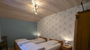 Ein Schlafzimmer mit zwei Holzbett, einer Holzbalkendecke und einer Wand mit einem Grasmuster.