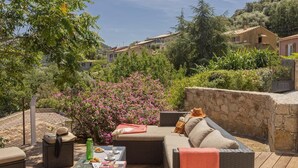 Un patio con mobiliario de mimbre, una mesa con aperitivos y un muro de piedra.