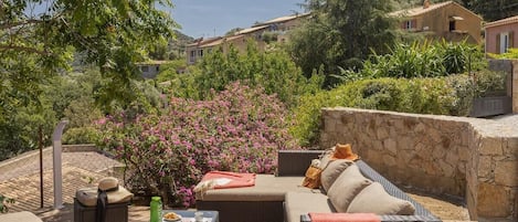 Une terrasse dotée de meubles en osier, une table avec des collations et un mur en pierre.