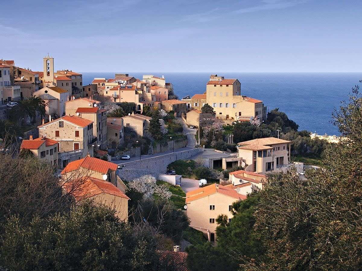 A coastal village with buildings, a road, and a view of the sea.