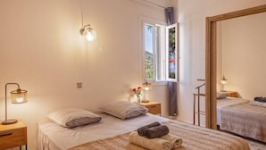 Un dormitorio con cama, mesita de noche, lámpara, ventana y espejo.
