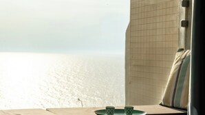A room with a view of the sea, a window with a grid pattern, and a table with two cups. - Netanya Beach & Pool Stay by Sea N' Rent (Netanya)