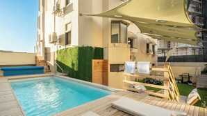 A rooftop pool area with a wooden deck, lounge chairs, and a small hot tub. - Netanya Beach & Pool Stay by Sea N' Rent (Netanya)