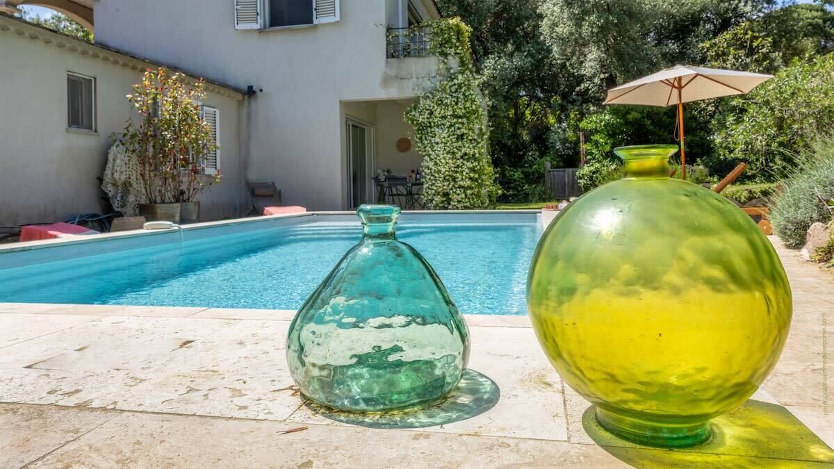 Una piscina con una bottiglia di vetro e una sfera di vetro sul bordo.