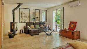 A modern living room with a sofa, a coffee table, a fireplace, a bookshelf, and a large window. - Casa Murati (Sisco)
