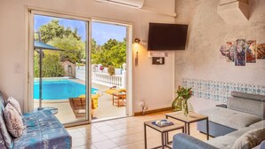 Una sala de estar con vista a una piscina, un televisor de pantalla plana y una pared con diseño.