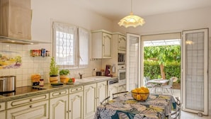 Una cocina con armarios blancos, un microondas, un lavabo y una zona de comedor con una mesa y sillas.