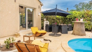 Un patio con muebles de exterior, una piscina y vistas a una casa con puerta corrediza de vidrio.