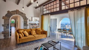 Ein geräumiges Wohnzimmer mit einer Couch, einem Couchtisch und Blick ins Freie durch große Fenster.