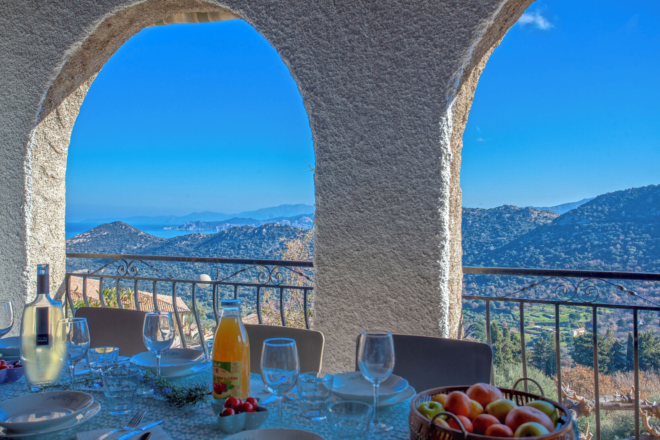 A table set for dining with a view of mountains and a clear sky.