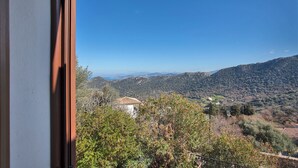 Blick aus einem Fenster auf eine gebirgige Landschaft, im Hintergrund ein Gebäude.