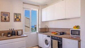 A compact kitchen with a washing machine, microwave, and a small sink. - Casa Félicie (Calvi)