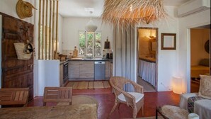 A cozy interior with a wooden dining table, wicker chairs, a kitchen with a modern design, and a large woven light fixture.