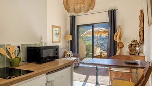 A kitchen with a microwave, wooden spoons, a green bowl, and a dining area with a table and chairs.