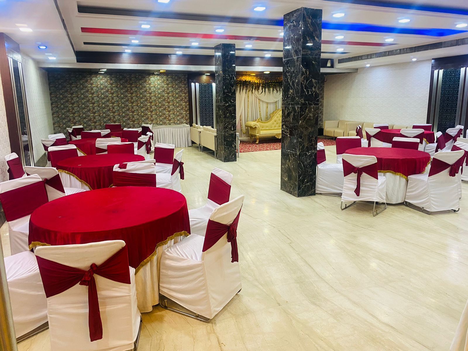 A banquet hall with round tables and chairs, a marble pillar, and a patterned wall.