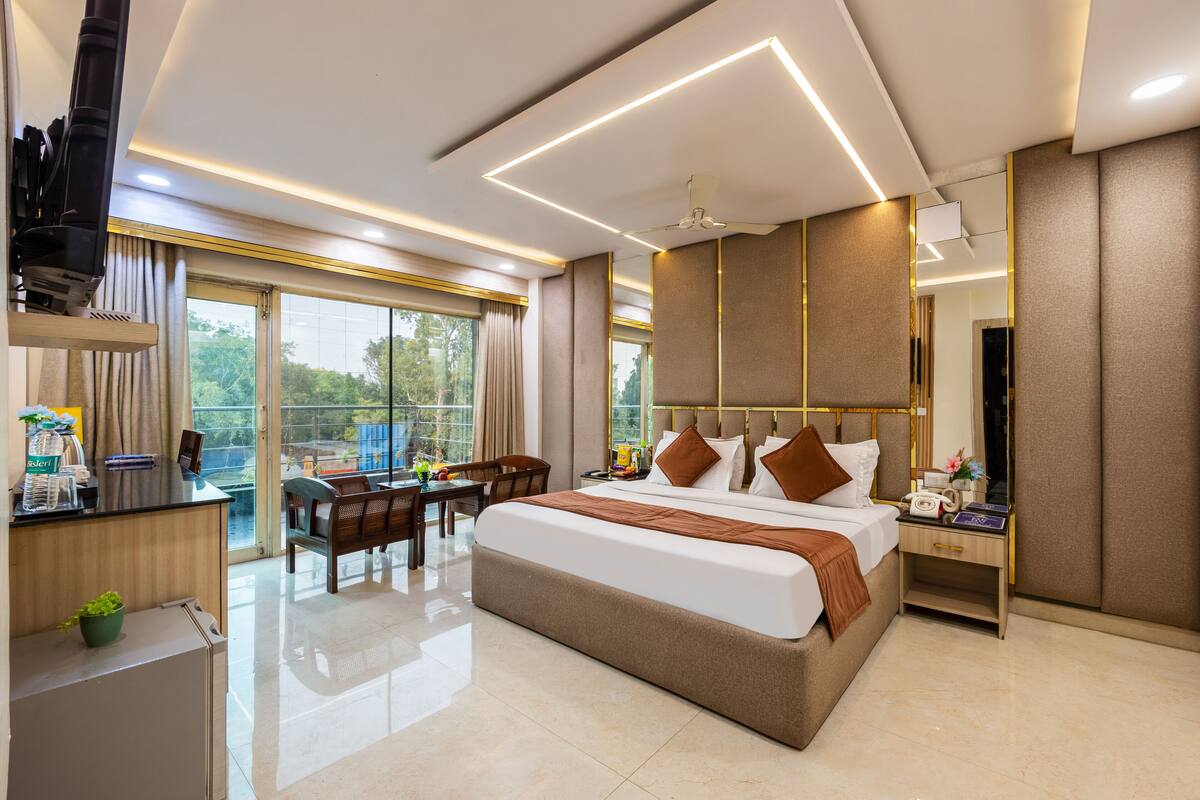 Une chambre d’hôtel moderne dotée d’un grand lit, d’un bureau, d’une chaise, d’une table à manger et d’un balcon avec vue.