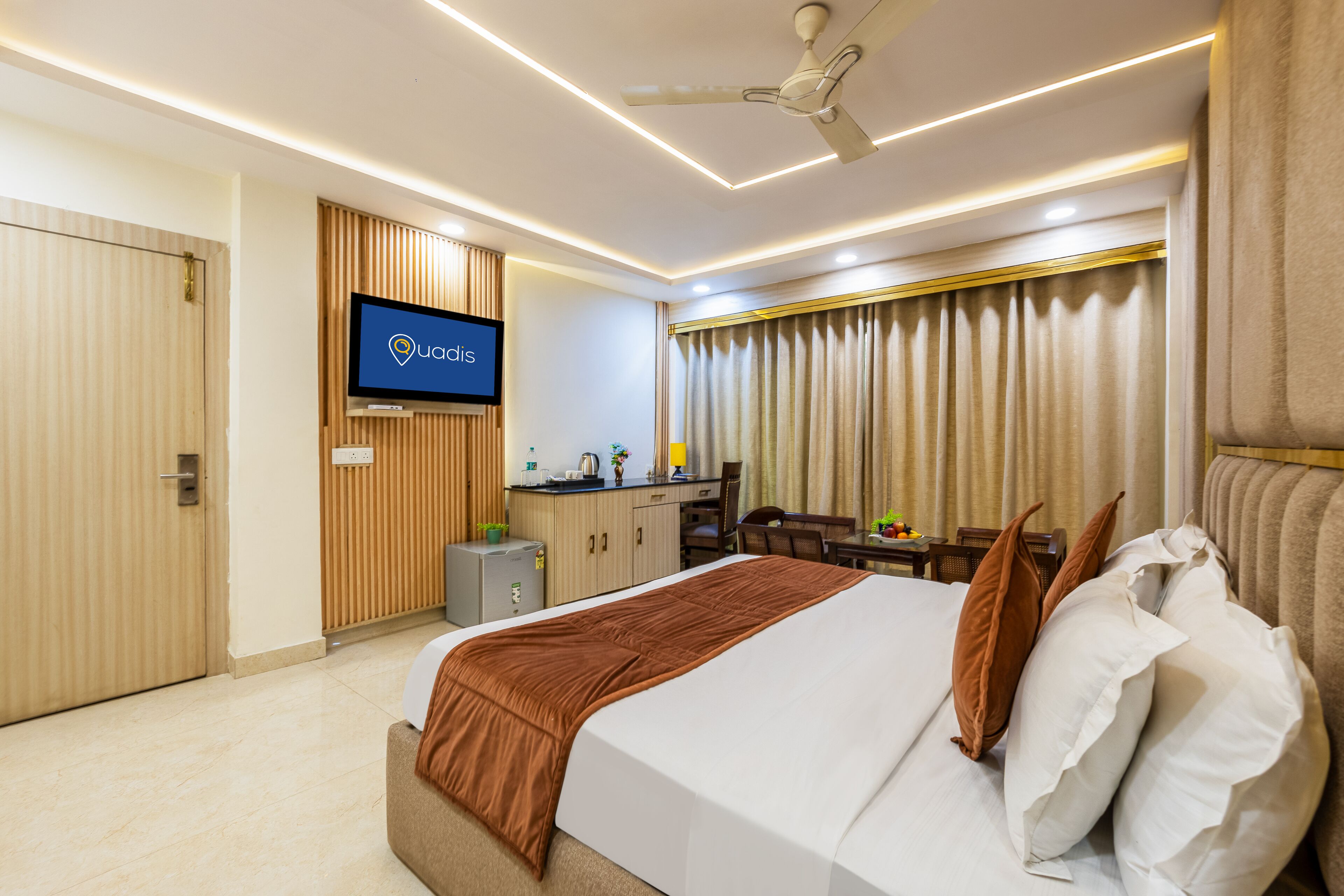 A hotel room with a bed, a desk, a television, and a ceiling fan.