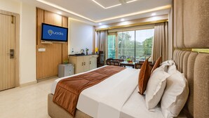 A hotel room with a bed, a TV, a desk, and a window with curtains.