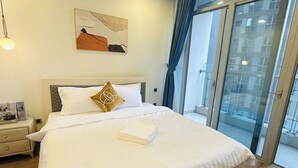 Camera d'albergo moderna con un letto grande, un comodino, un quadro appeso e vista attraverso la porta in vetro.