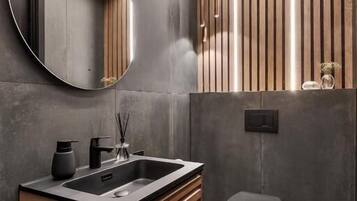 A modern bathroom with a wooden vanity, a round mirror, and a black toilet.