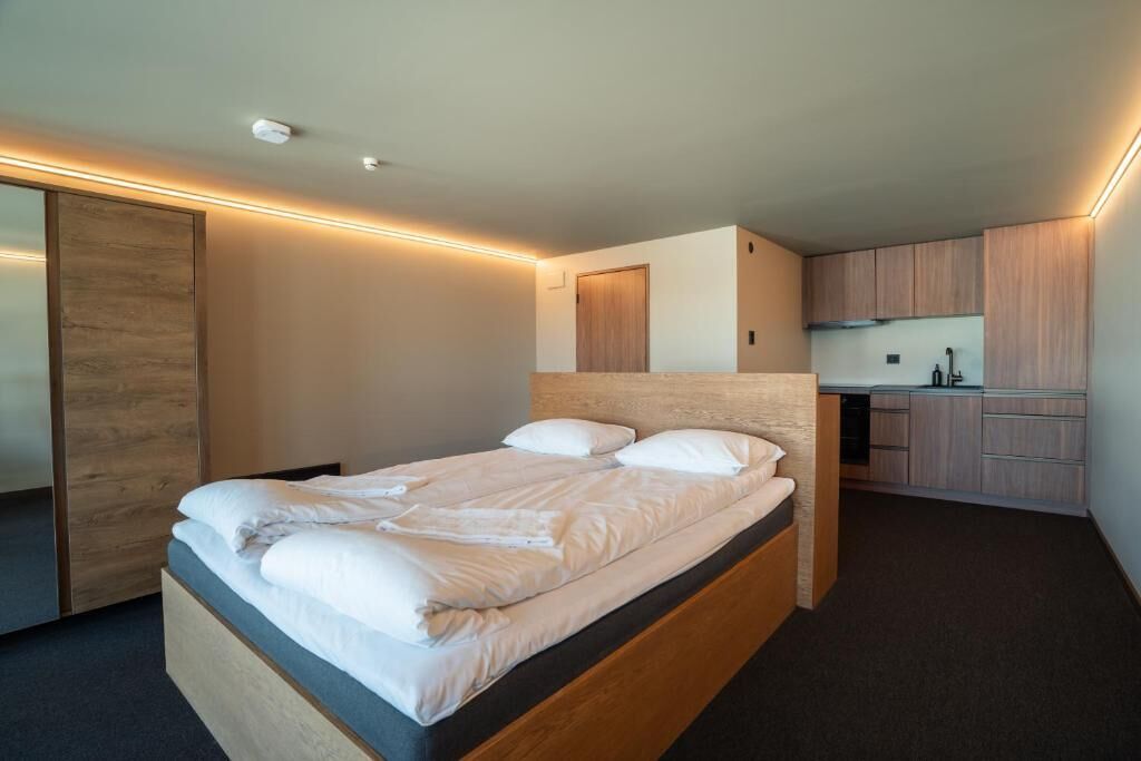 Un dormitorio moderno con una cama de madera, un escritorio integrado y una kitchenette.