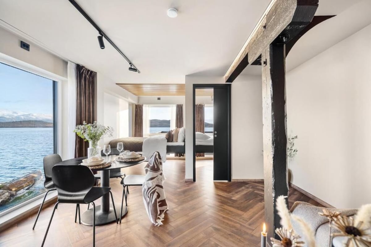 Ein modernes Interieur mit Essbereich, einer Couch und Blick auf das Wasser.