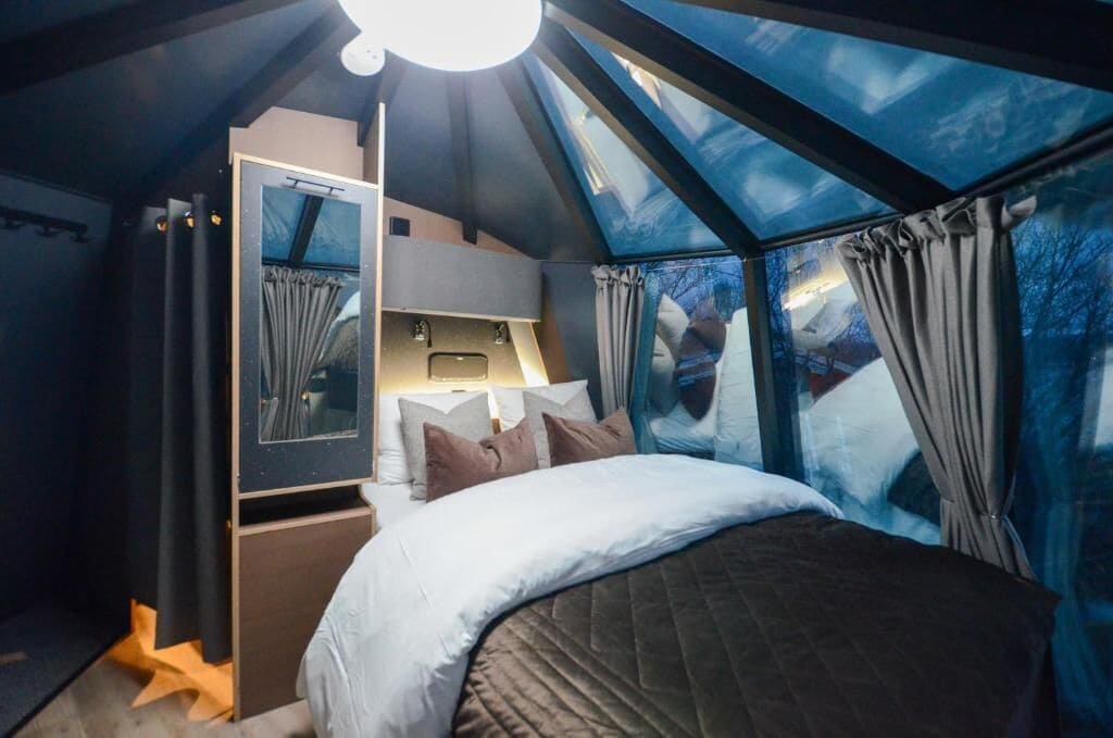 Un dormitorio con tragaluz, una cama, una mesita de noche y un espejo.