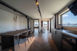 Eine moderne Küche mit einer großen Kochinsel, einem Essbereich mit Stühlen und Bergblick durch das Fenster.
