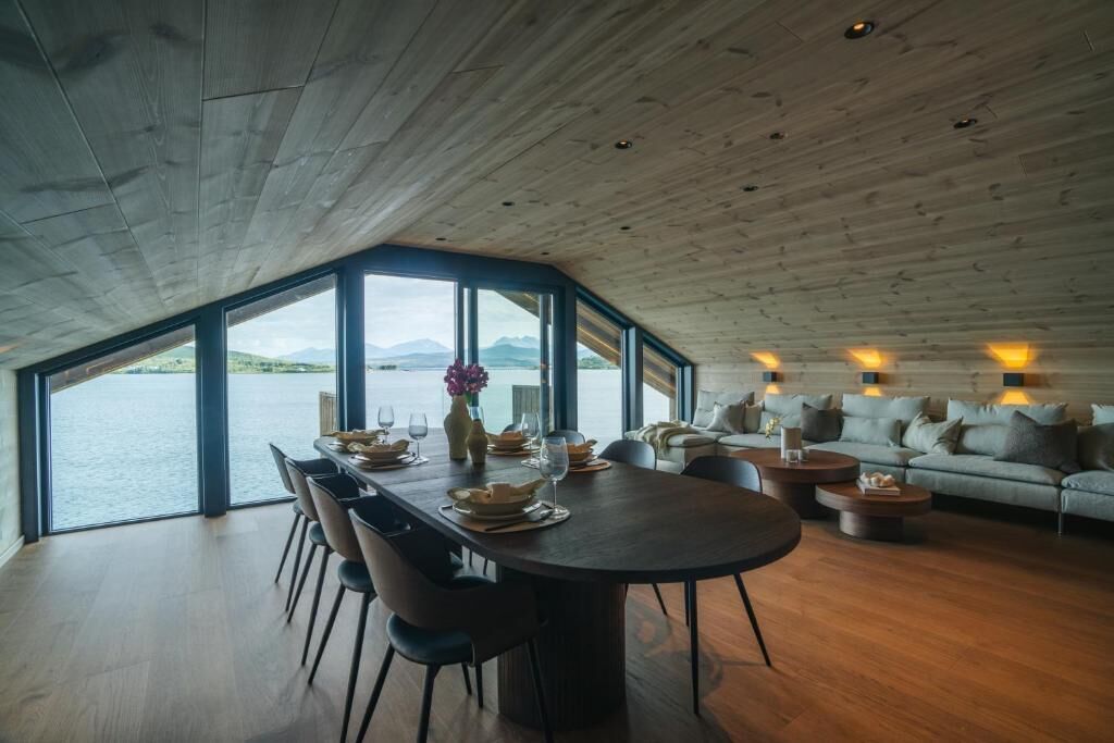 Un espace repas comprenant une grande table, des chaises et une vue sur l’eau.