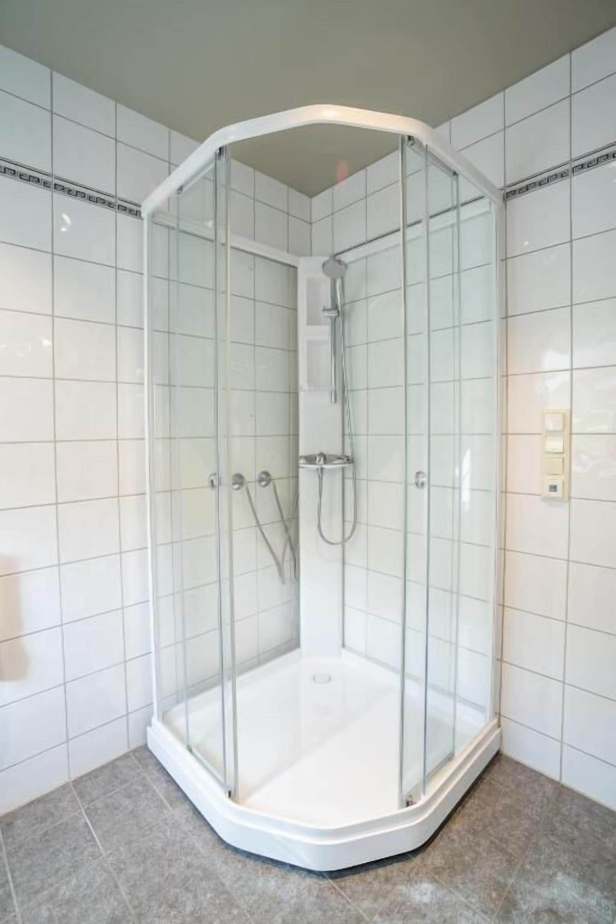 A corner shower enclosure with clear glass doors and a white tiled interior.