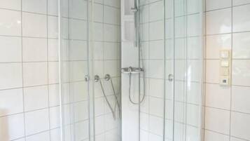 A corner shower enclosure with clear glass doors and a white tiled interior.