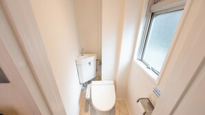 Un baño pequeño y estrecho con un inodoro, un lavamanos y una ventana.