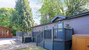 Eine Holzhütte mit umzäunter Terrasse, einer kleinen Veranda und einer Garage.