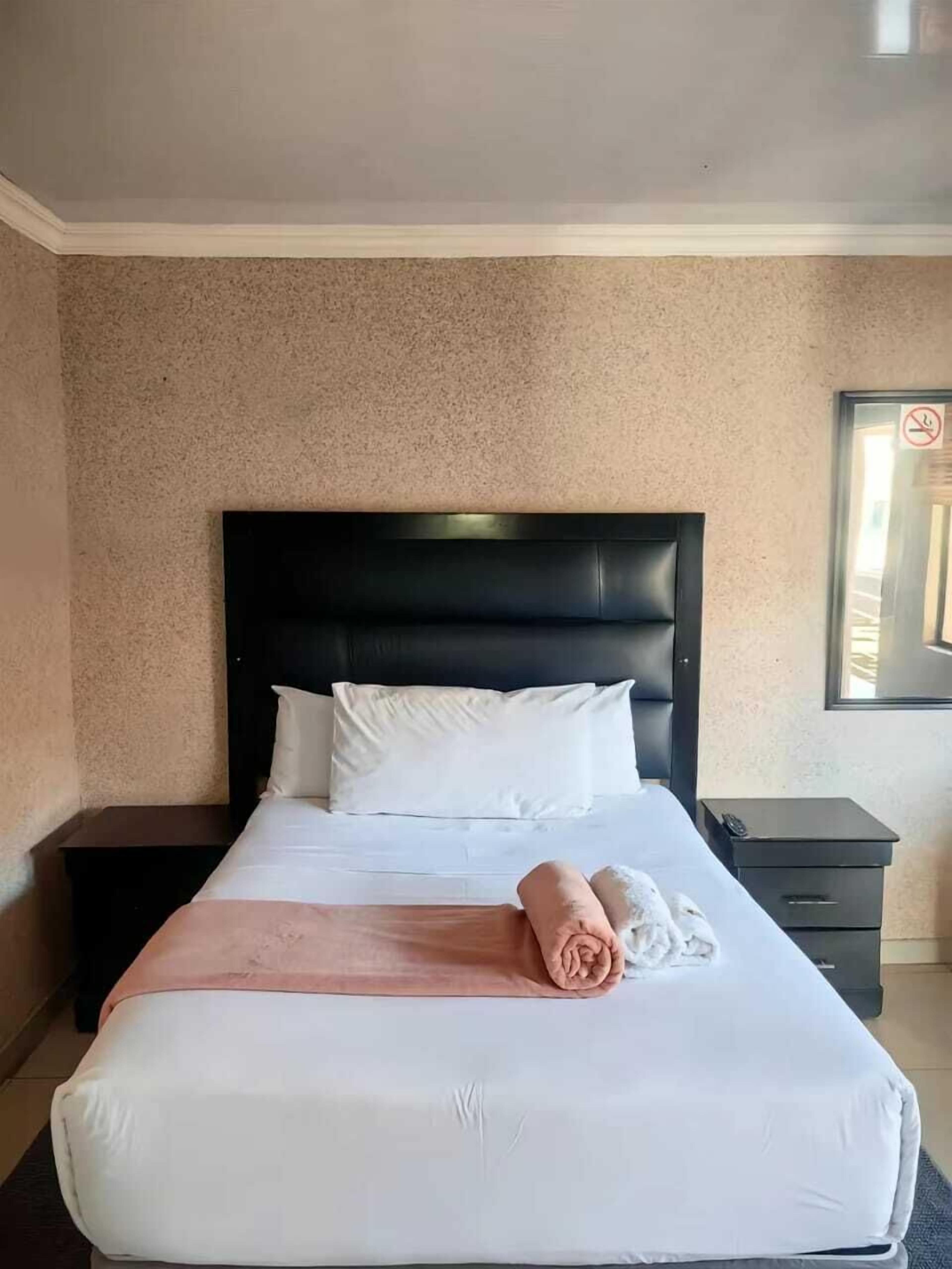A hotel room with a bed, a nightstand, a wall-mounted TV, and a window with a view.