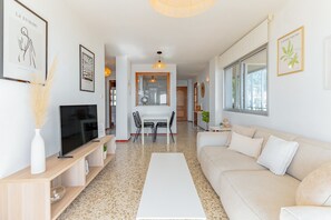 Un salon moderne comprenant un téléviseur, un canapé, une table basse et un coin repas.