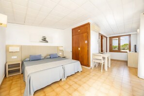 Une chambre à coucher comprenant un lit, des tables de chevet, une armoire en bois, un bureau et une fenêtre donnant sur un beau paysage.