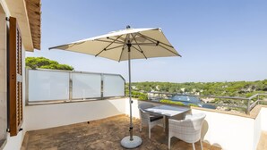 A balcony with a table and chairs, a large umbrella, and a view of a coastal landscape. - Studio Apartment 'Estudio Vistas Al Mar' with Sea View, Wi-Fi and Air Conditioning (Cala Figuera)