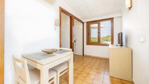 A room with a dining table, chairs, a TV, and a window with a view. - Studio Apartment 'Estudio Vistas Al Mar' with Sea View, Wi-Fi and Air Conditioning (Cala Figuera)
