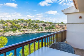 A balcony with a view of a rocky coastline and a clear blue sea.