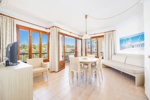 A spacious room with a dining table, chairs, a sofa, and a TV.