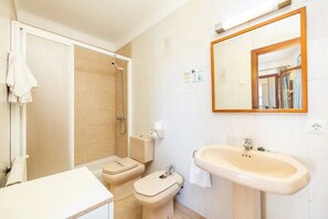A bathroom with a shower, toilet, sink, and mirror.