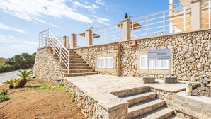 A stone building with a staircase leading to a balcony, a sign indicating a private pool, and a clear sky.