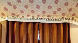 A room with a wooden table and two chairs, a patterned ceiling, and brown curtains. - Road to Heaven Resort (Bhuj)