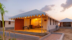 A traditional building with a covered patio, a seating area with chairs, and a staircase leading to the entrance. - Road to Heaven Resort (Bhuj)