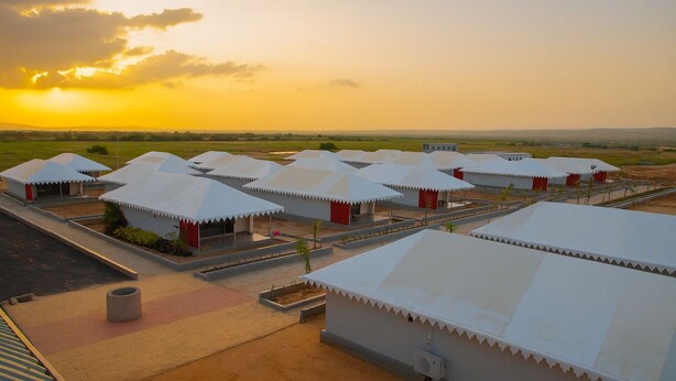 A row of white-roofed buildings with red accents, arranged in a linear fashion with a paved walkway in between. - Road to Heaven Resort (Bhuj)