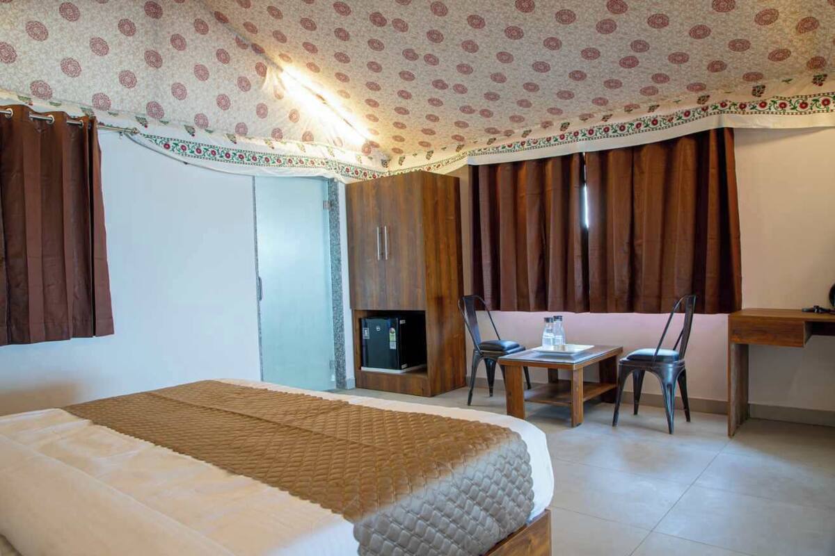 A hotel room with a bed, a desk, a chair, and a television.