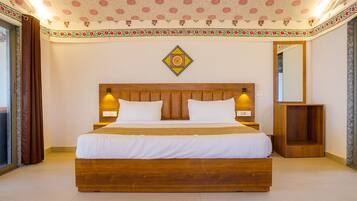 A hotel room with a large wooden bed, two bedside lamps, a decorative wall hanging, and a mirror on the wall.